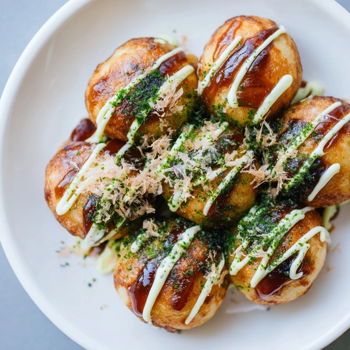 Crispy Japanese Takoyaki sprinkled with dried seaweed and mayonnaise on a plate