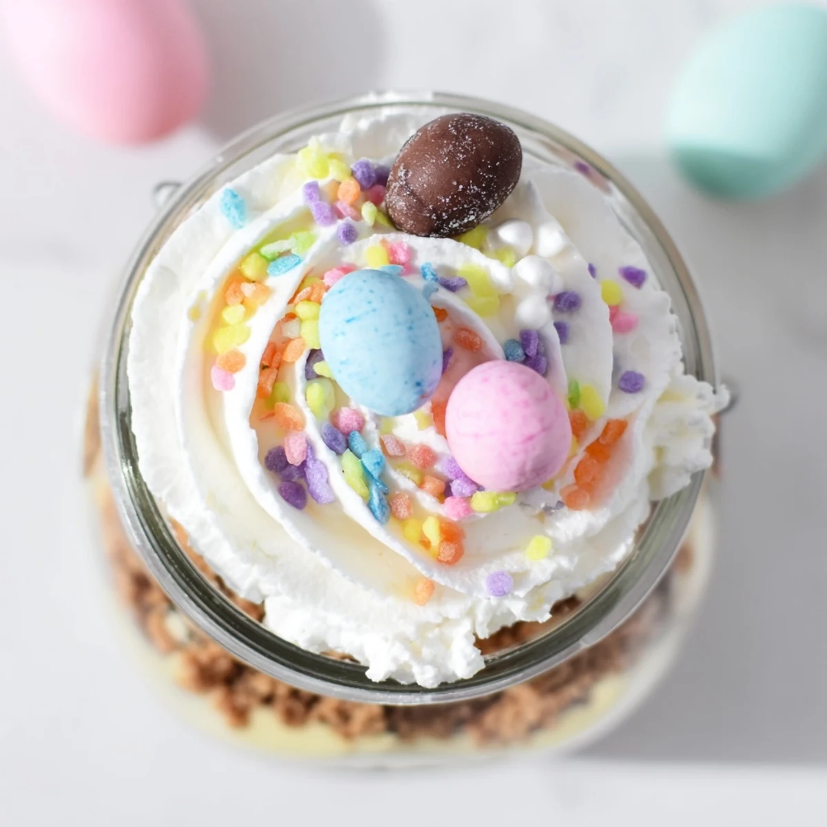 Individual Easter Egg Cheesecake jars revealing chocolate eggs nestled inside the no-bake cheesecake layers