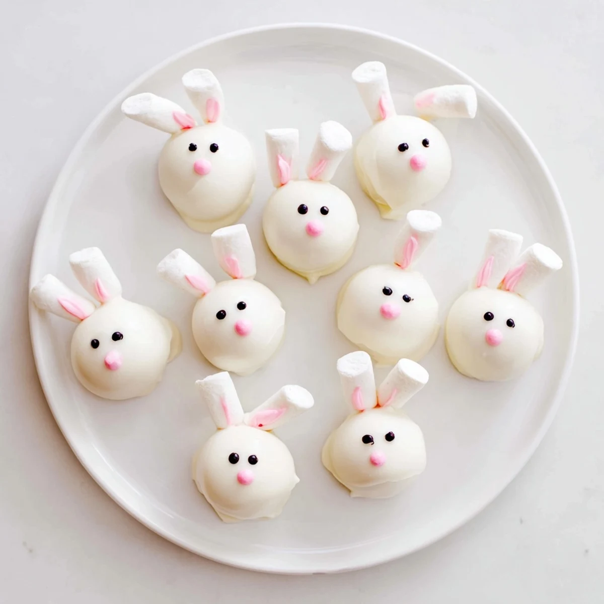 White chocolate-coated Bunny Oreo Balls with cute marshmallow ears and tails arranged on serving platter