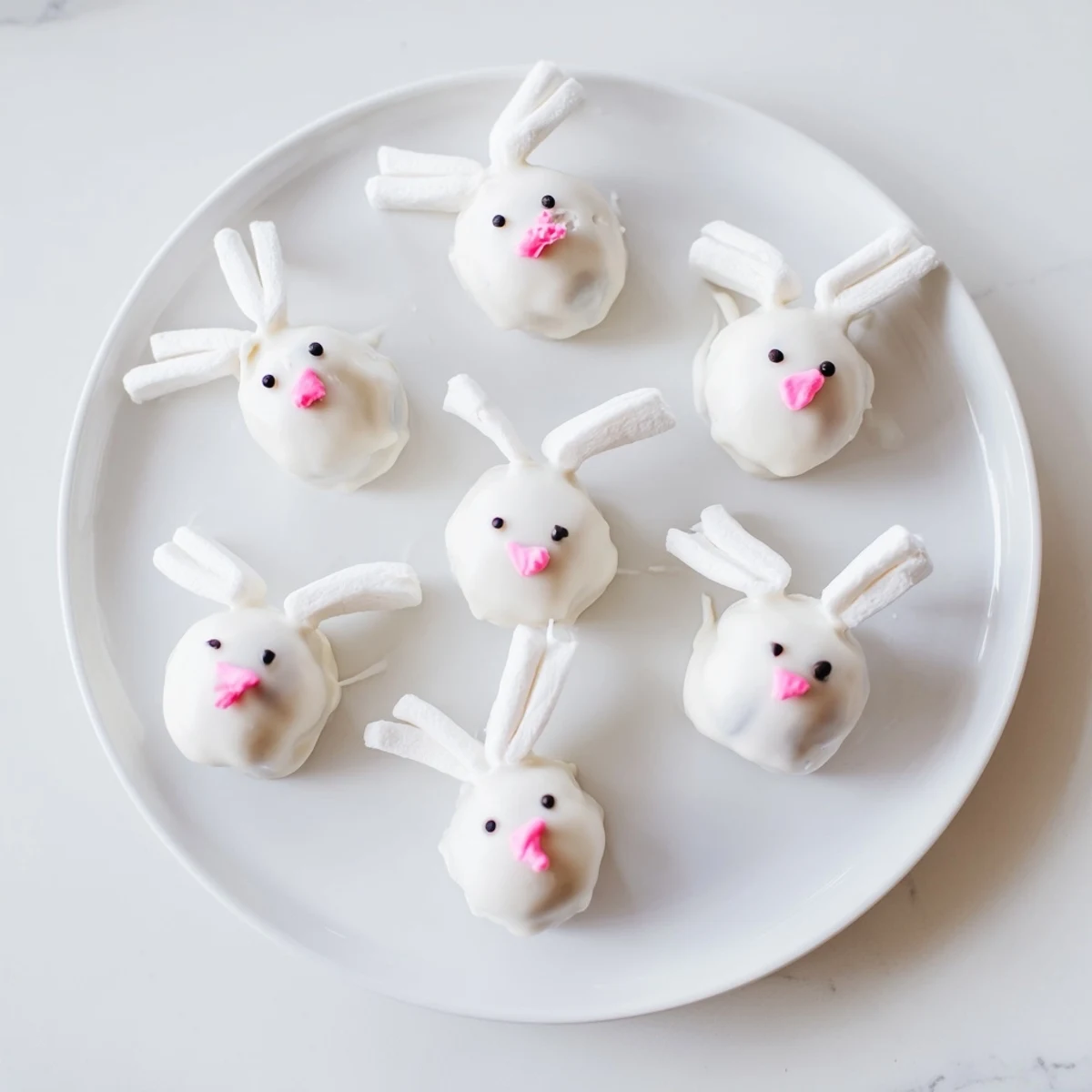 Creamy chocolate-dipped Bunny Oreo Balls decorated with edible eyes and fluffy marshmallow tails for spring
