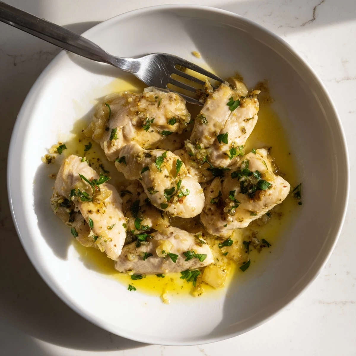 Melt-in-your-mouth garlic butter chicken crockpot meal garnished with fresh parsley and lemon