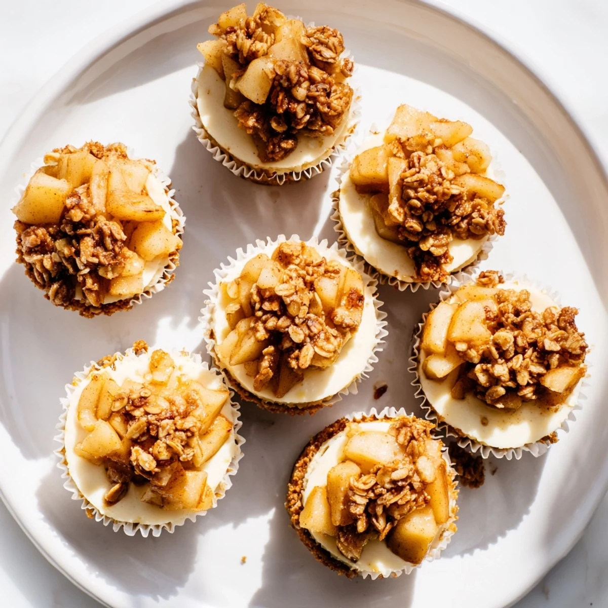 Rich and velvety mini cheesecakes featuring a buttery crust beneath sweet spiced apple crisp layer