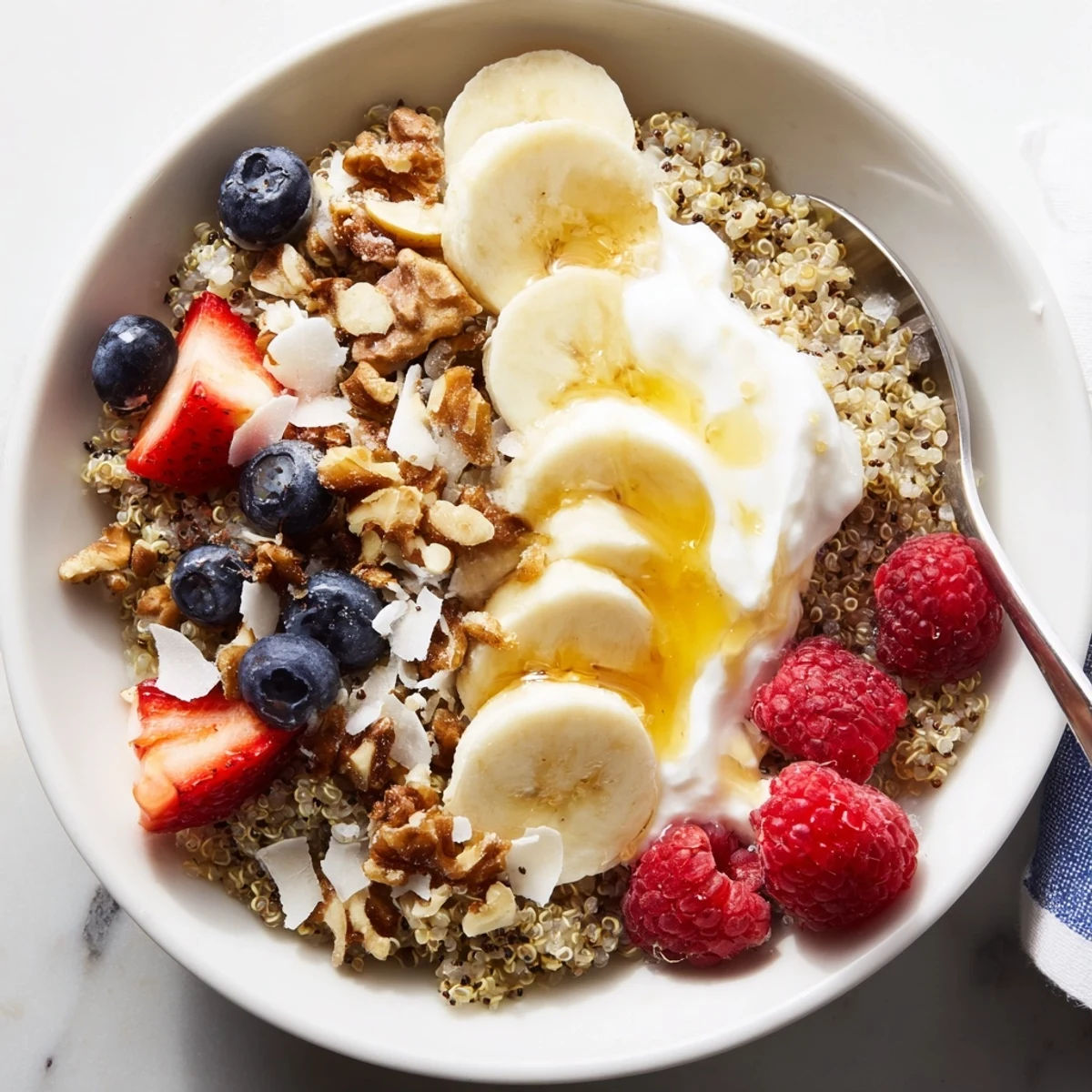 Quinoa Breakfast Bowl topped with creamy yogurt, sliced banana, crunchy nuts