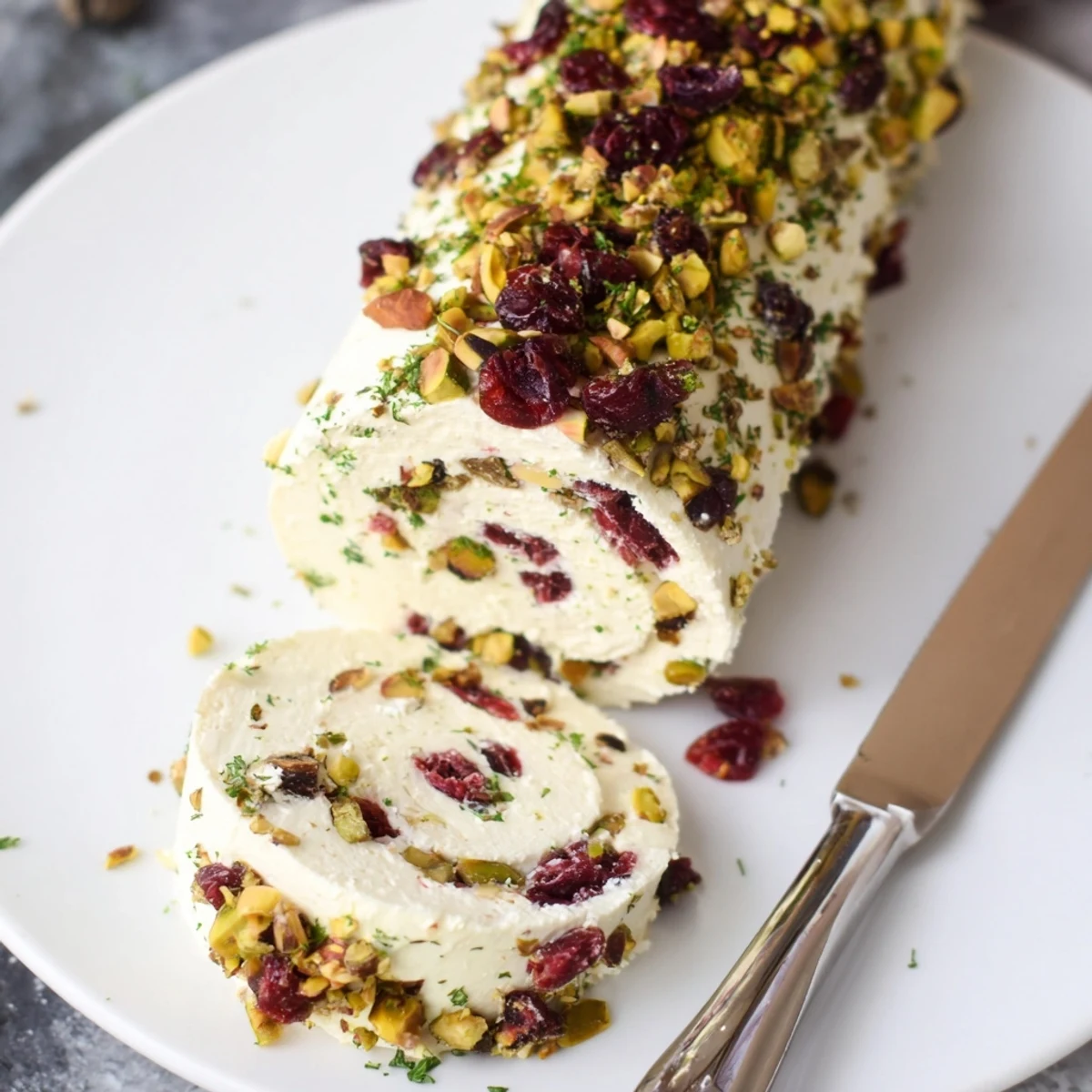 Cranberry Pistachio Cheese Log rolled in chopped nuts, ready with crackers