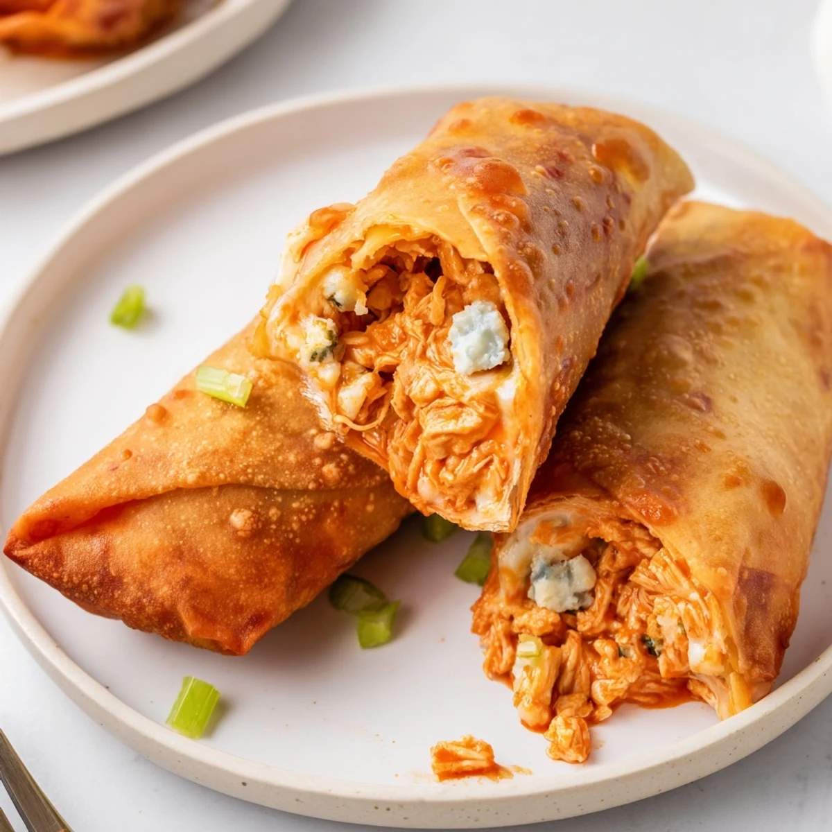 Spicy, cheesy filling oozing from fried egg rolls — Buffalo Chicken Egg Rolls Recipe