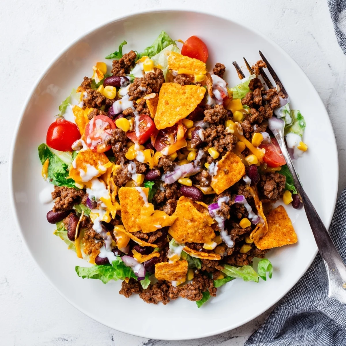 Warm Simple Doritos Taco Salad topped with skillet-seasoned beef and crushed chips