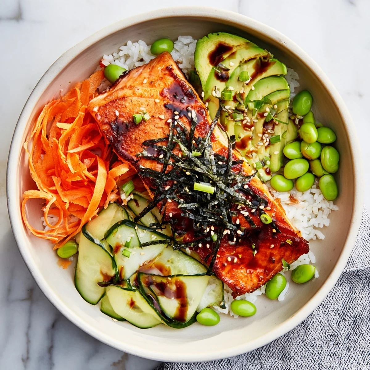 Golden crispy salmon and rice bowl topped with fresh avocado, cucumber, and savory soy ginger sauce