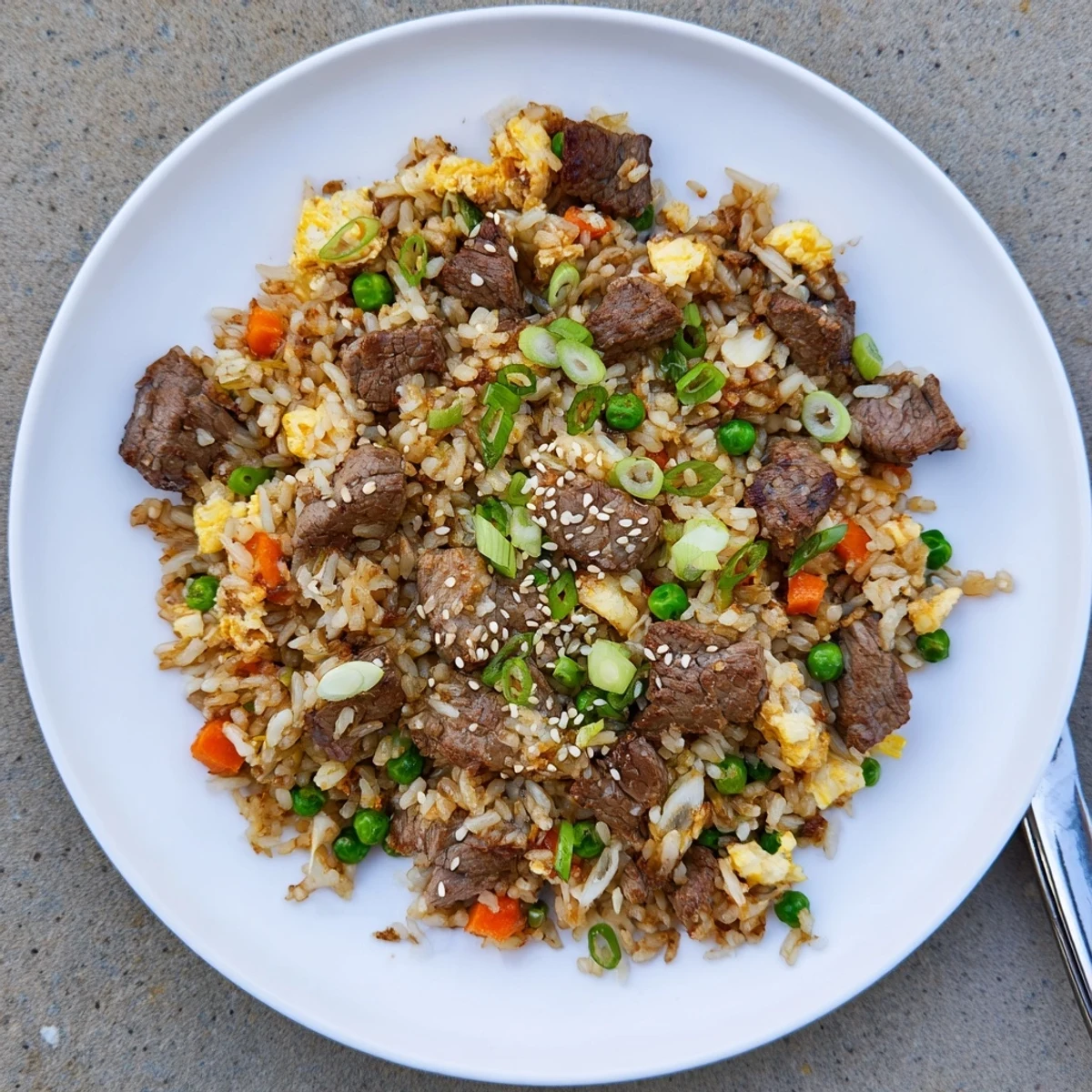 Sizzling Blackstone hibachi steak fried rice with tender beef cubes and colorful vegetables on a flat top griddle