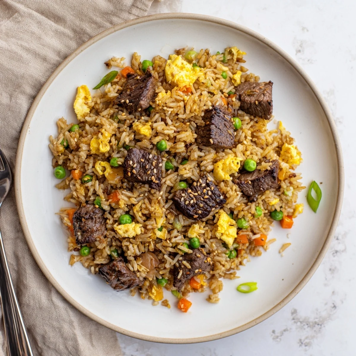 Golden fried rice loaded with marinated steak, peas, carrots, and scrambled eggs cooked on a Blackstone griddle