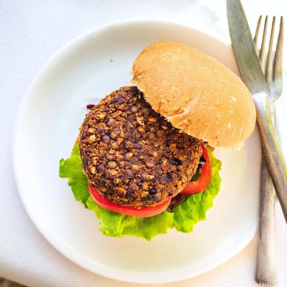 Golden brown veggie burger patties sizzling in a skillet with visible black beans and colorful diced vegetables