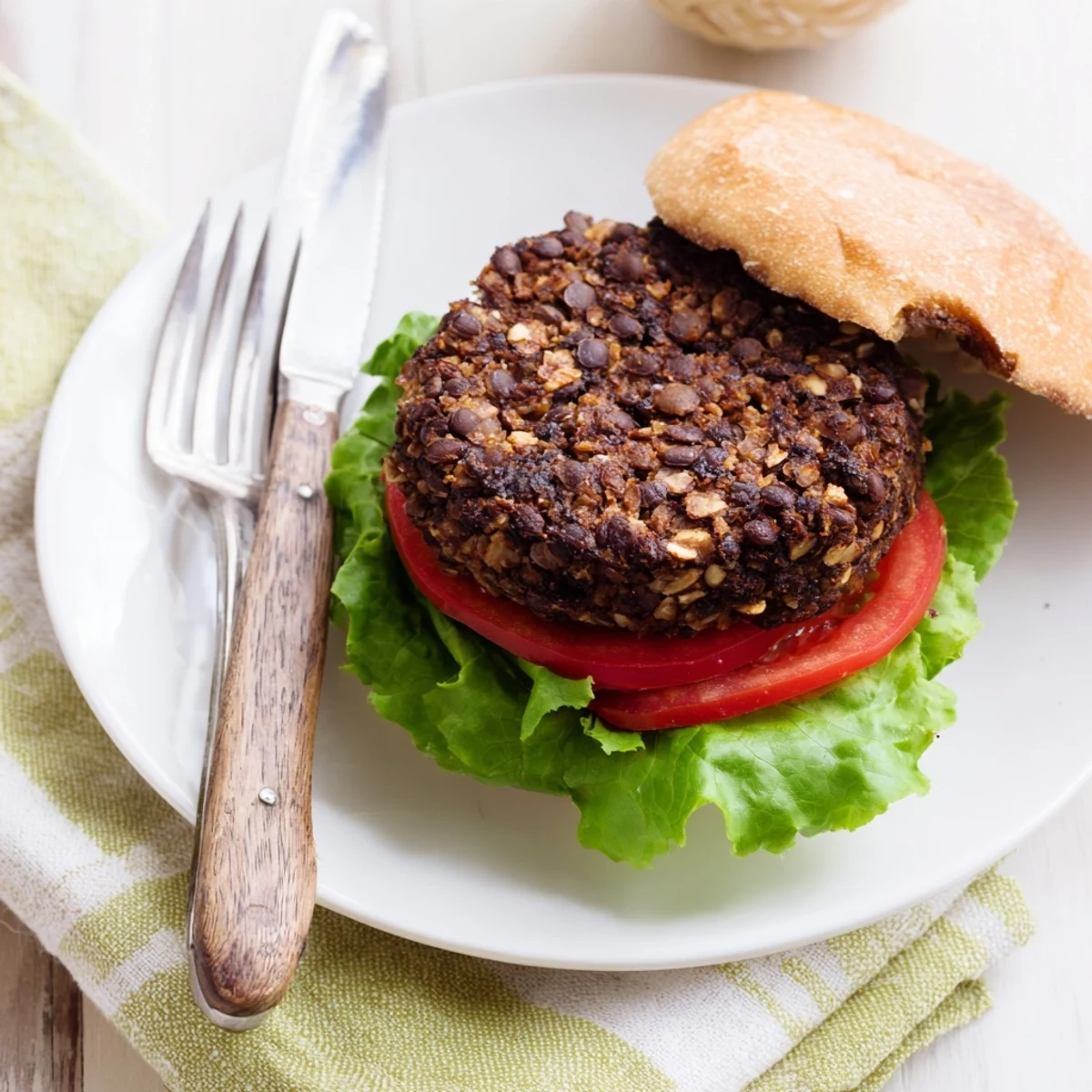 Hearty veggie burger stacked on a toasted bun with fresh lettuce, tomato slices, and creamy avocado