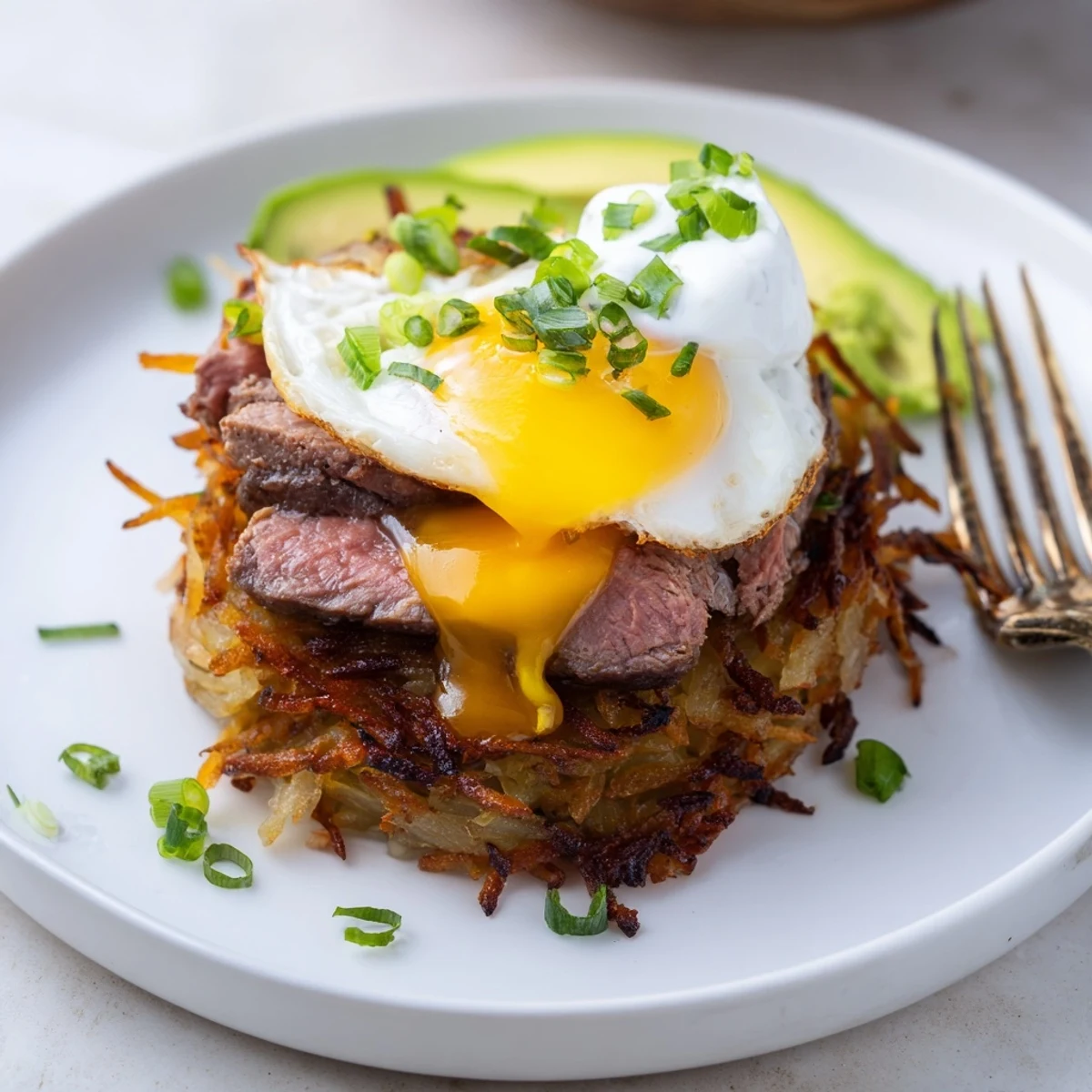 Loaded Steak Egg Hash Brown Stacks topped with melted cheddar and avocado