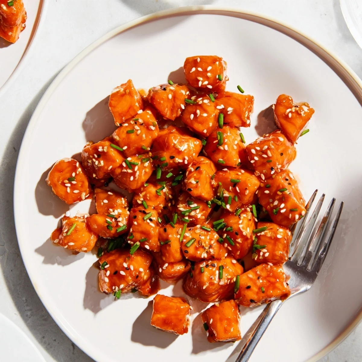 Crispy hot honey salmon bites coated in a glistening, spicy-sweet sticky glaze on a baking sheet