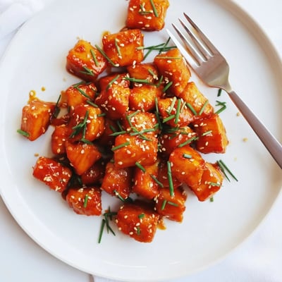 Golden hot honey salmon bites drizzled with sauce and sprinkled with sesame seeds and chives